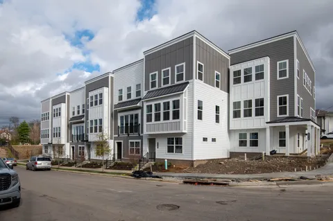 a front view of a building with lot of cars and trees