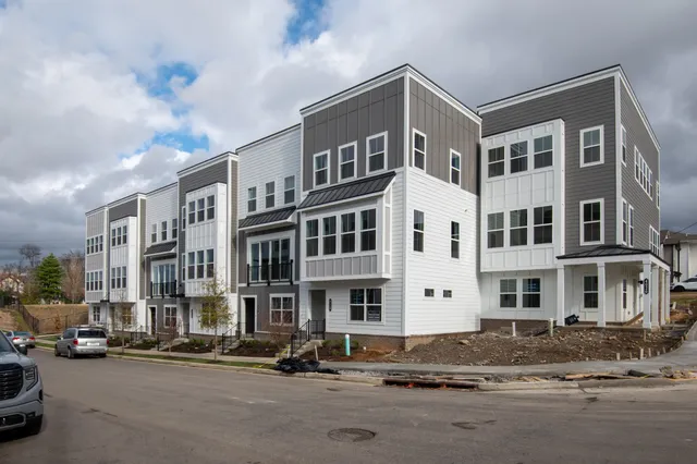 a front view of a building with lot of cars and trees