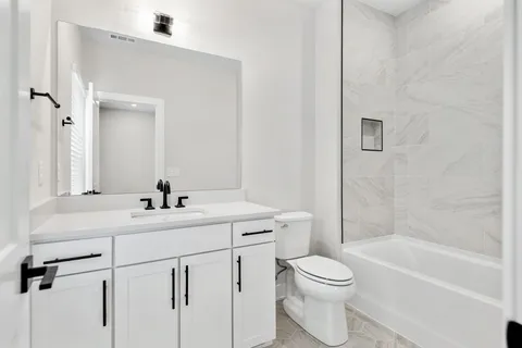 a bathroom with a toilet a sink a mirror a bathtub and vanity