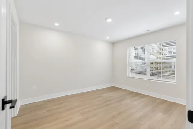 an empty room with wooden floor and windows