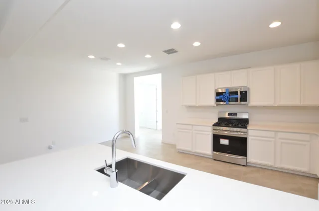 a kitchen with granite countertop a stove a sink and a microwave