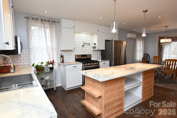 a kitchen with stainless steel appliances granite countertop a refrigerator a stove a sink and white cabinets with wooden floor