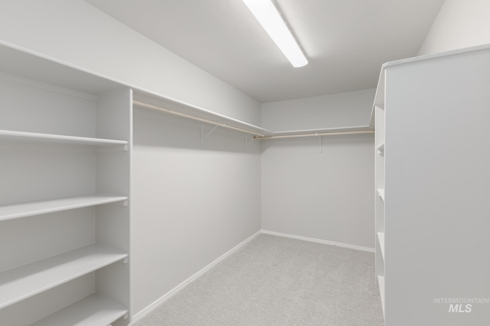 12842 Ropers Street Nampa, ID 83651 - Photo 29 of 29 Walk-in closet featuring light gray carpeting, extensive built-in shelving, and multiple clothing rods