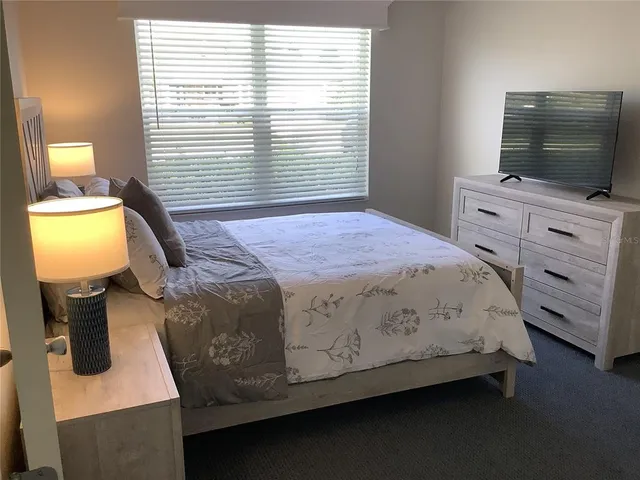 a bedroom with a bed and a flat tv screen on the dresser