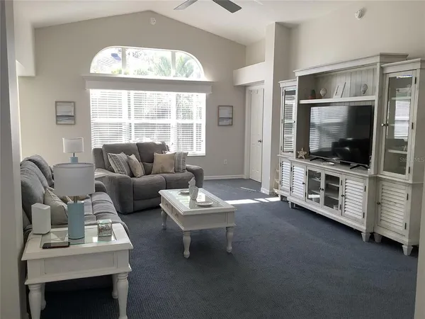 a living room with furniture a flat screen tv and a large window