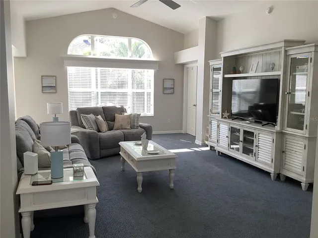 a living room with furniture a flat screen tv and a large window