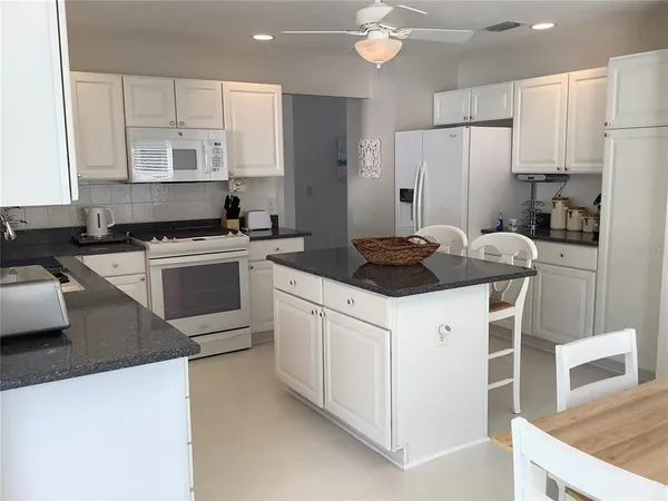 a kitchen with stainless steel appliances a stove a sink a refrigerator and white cabinets