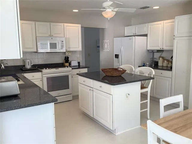 a kitchen with stainless steel appliances a stove a sink a refrigerator and white cabinets