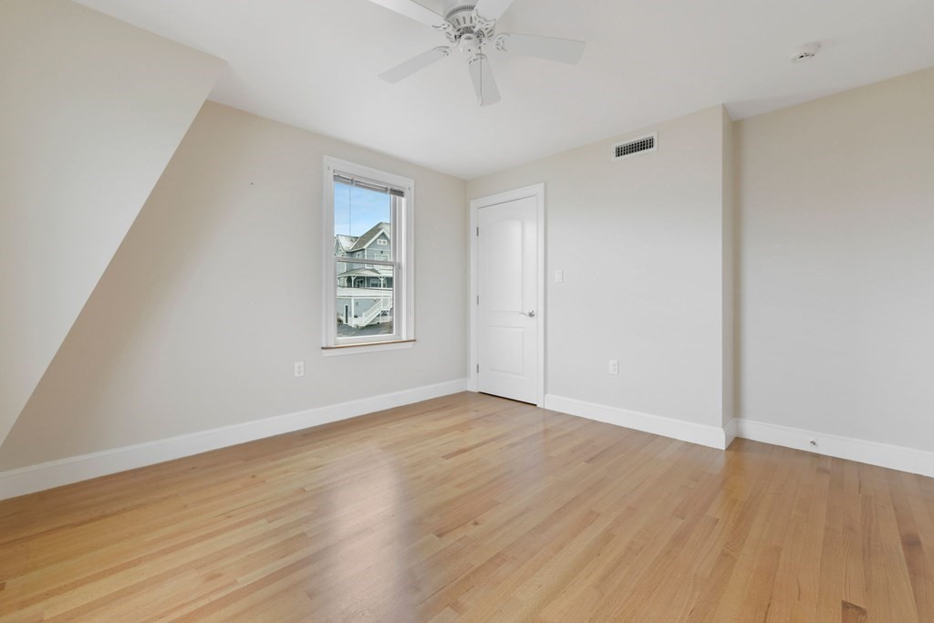 16 Burr Road Hull, MA 02045 - Photo 18 of 25 an empty room with wooden floor chandelier fan and windows