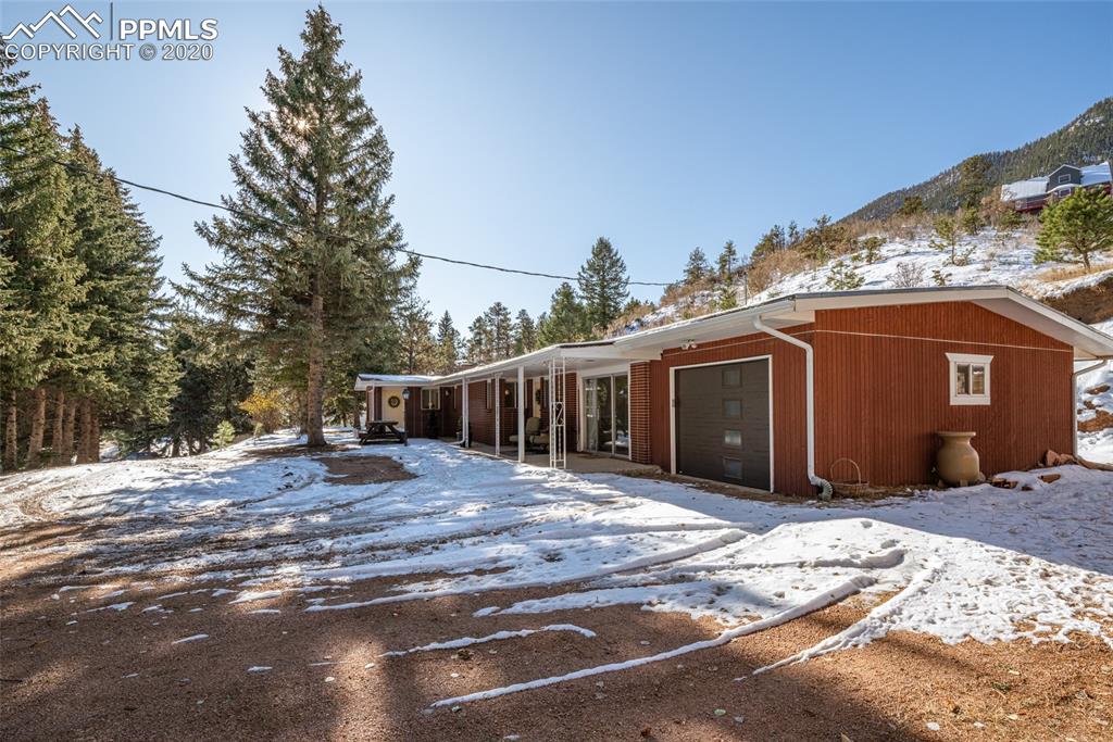 8715 Chipita Park Road Cascade, CO 80809 - Photo 7 of 33 View of the driveway entrance to the home lined with tall pine trees.