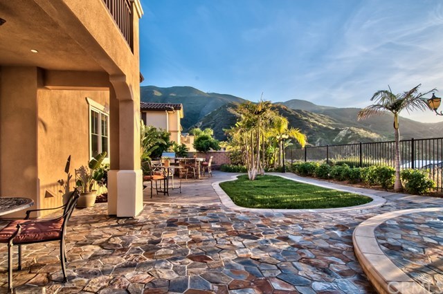 2148 Sageleaf Circle Corona, CA 92882 - Photo 2 of 74 Anchored by sweeping views of the dazzling landscape, this backyard features an outdoor kitchen, tropical landscaping with professional lighting, expansive flagstone areas and an outdoor living area with a fire pit