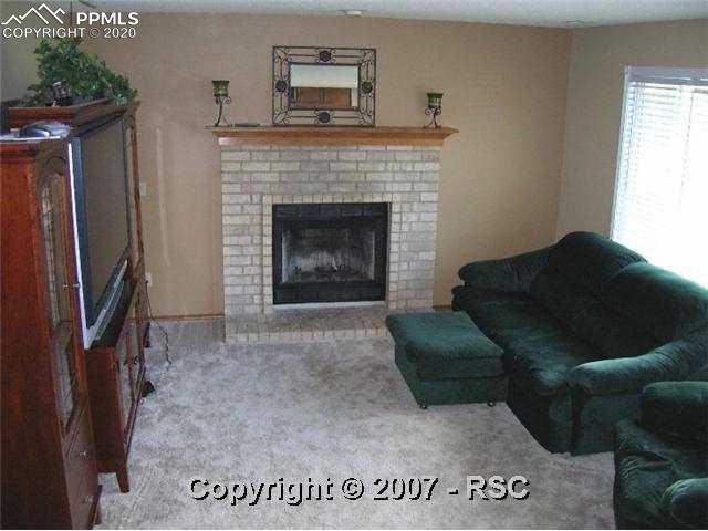 7832 Swiftrun Road Colorado Springs, CO 80920 - Photo 3 of 6 Family room with fireplace. Newer carpet and paint.