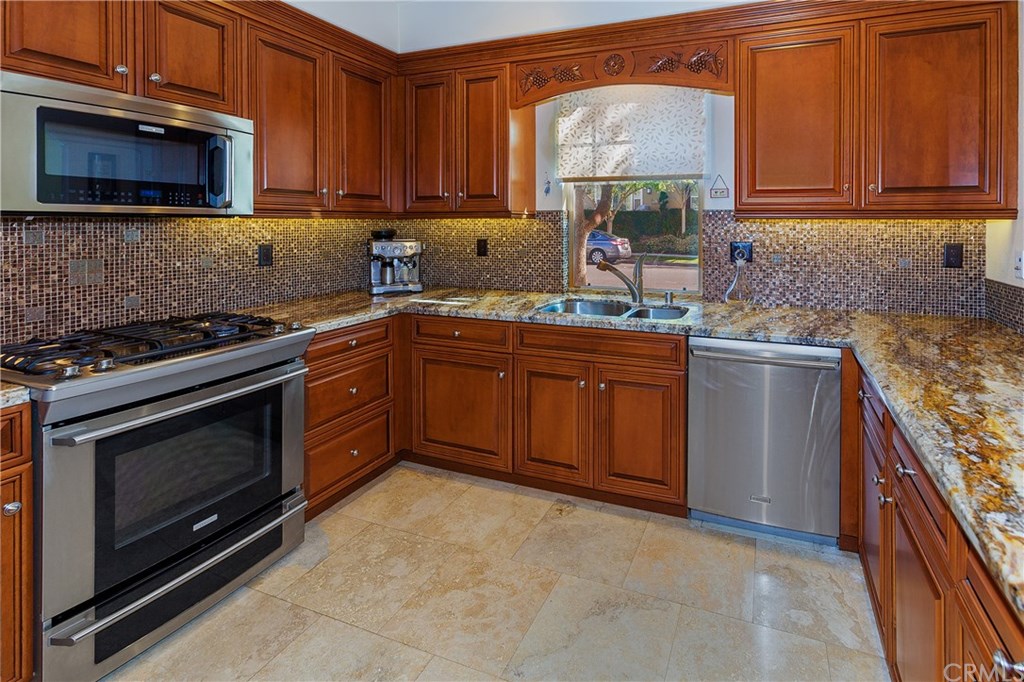 61 Zinnia Street Ladera Ranch, CA 92694 - Photo 1 of 1 Beautifully upgraded kitchen hosts Travertine Tile Floors, lovely slab granite countertops, glass and Travertine petite mosaic tile backsplash and stainless appliances.