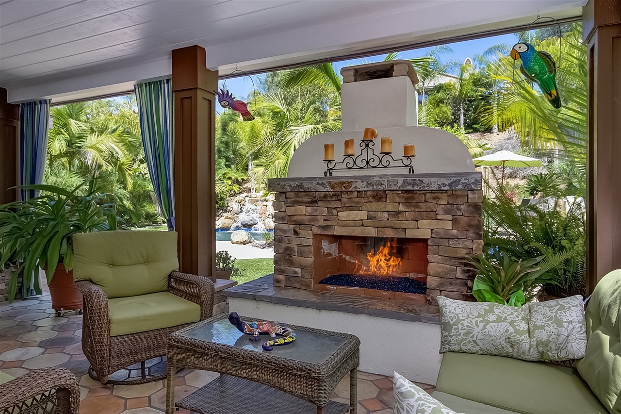 1853 Shadetree Drive San Marcos, CA 92078 - Photo 21 of 25 Fully Covered outdoor room with Beautiful stone faced gas fireplace, custom outdoor drapes, patio flooring is Saltillo and Terracotta tile.