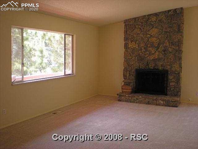 7930 Topeka Avenue Cascade, CO 80809 - Photo 3 of 10 Great room with attractive moss rock fireplace & large front picture window