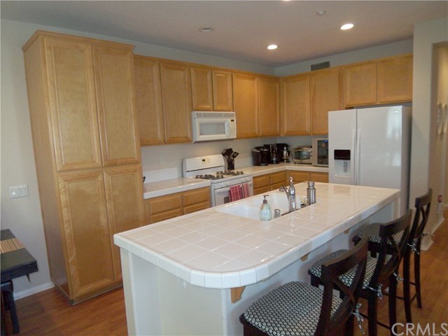 Light and Bright kitchen with large center island with breakfast counter/bar, white appliances, and honey toned Maple cabinets. (refrigerator not included)