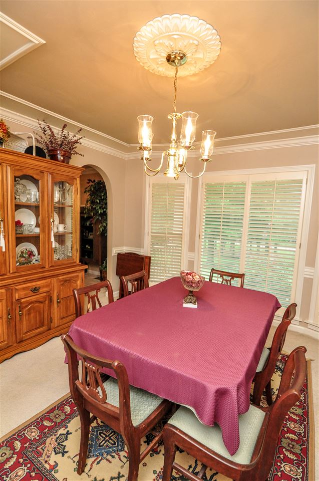 The formal dining room offers the ideal setting for any holiday gathering with extensive crown & chair moldings, large window, carpet, and elegant chandelier with medallion.