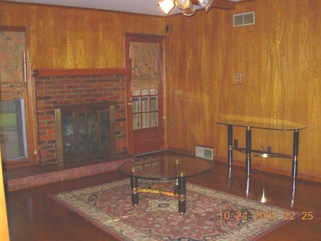 Spacious den w/beautiful wood paneling, hardwood floors and brick fireplace