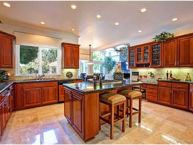 17036 Circa Del Sur Rancho Santa Fe, CA 92067 - Photo 4 of 25 The warmly accented kitchen with rich cabinets, granite counters, stone floors and a 6 burner gas cooktop, is open to the family room and has views of the pool area with gazebo.